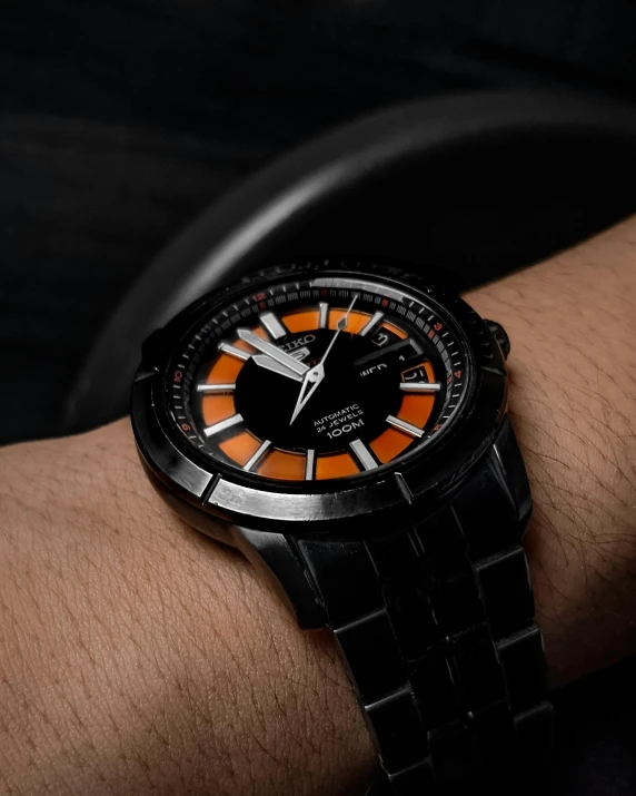 close up of man wrist holding a watch in black and orange