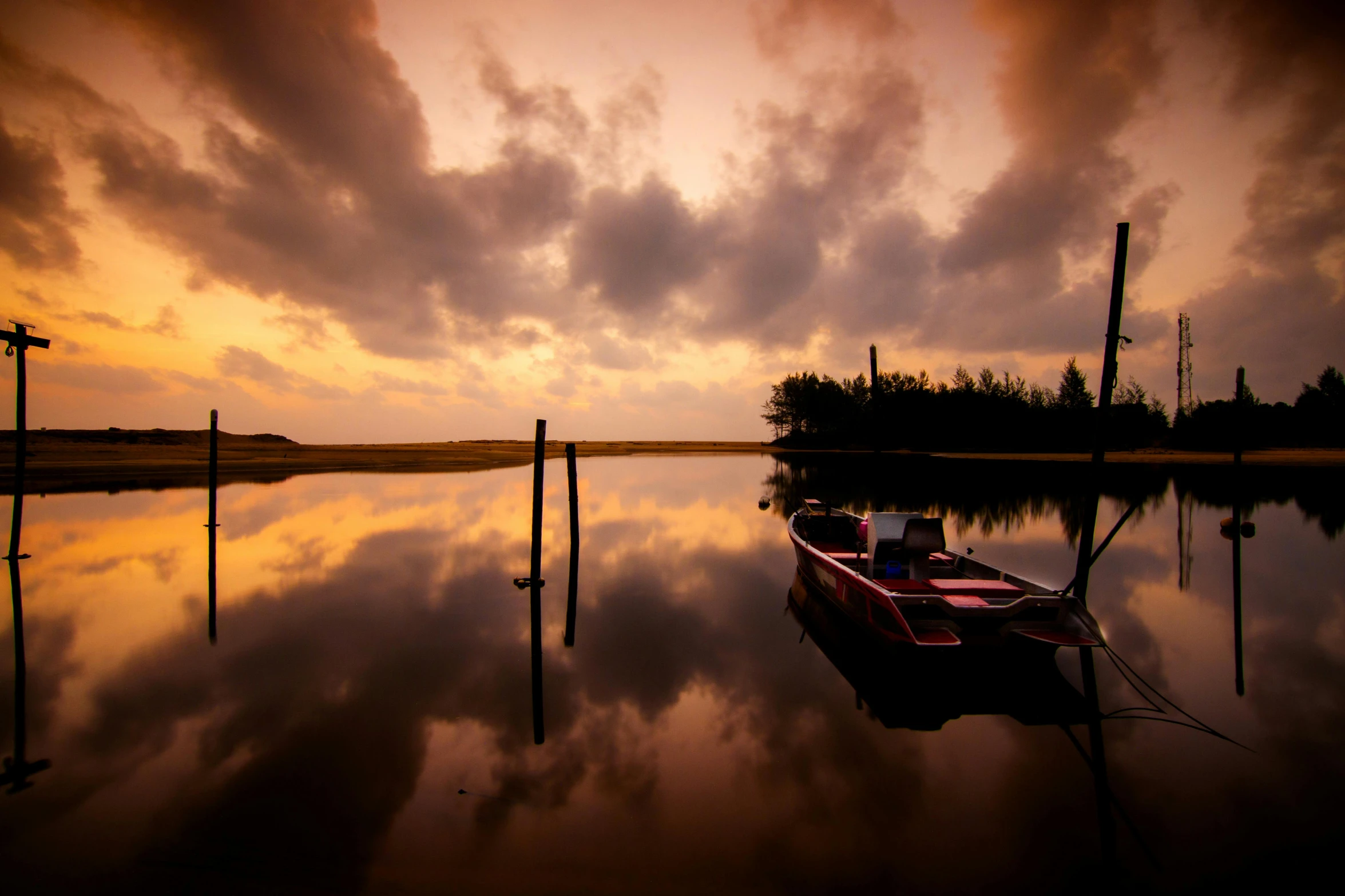 boat parked on a beach at sunset next to a wire