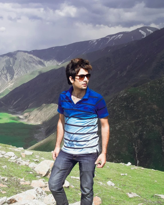 a young man standing on a mountain in sunglasses