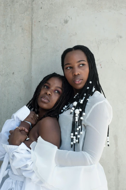 two young african americans hugging against a wall