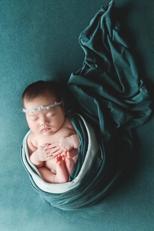 a baby is wrapped up and sleeping on blue blanket