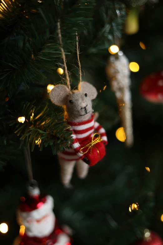 a toy bear in a striped sweater hanging on the christmas tree