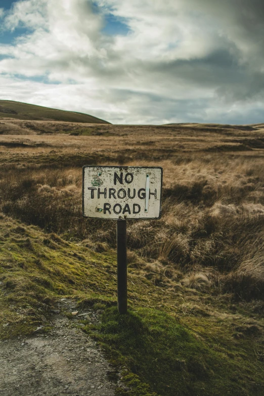 a sign on a path near some dry grass