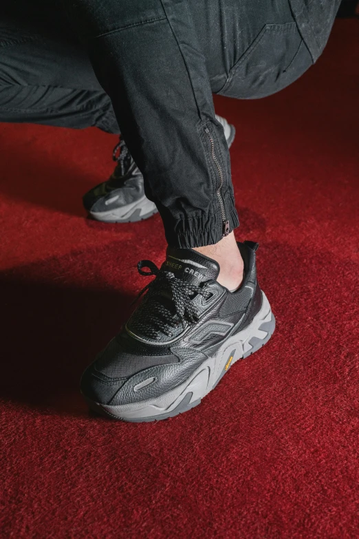 a person wearing shoes on top of a red carpet