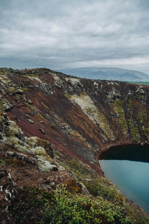 an ocean with a rock and green hillside with water