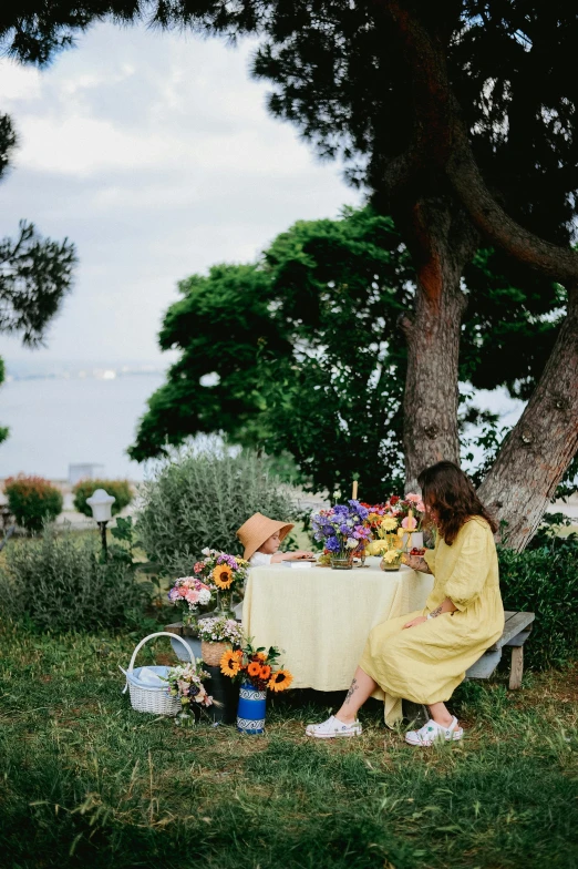 a woman sitting at a picnic table with flowers on it