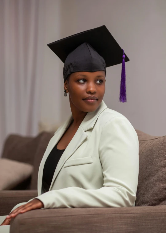 a woman in graduation cap and suit sitting on the couch