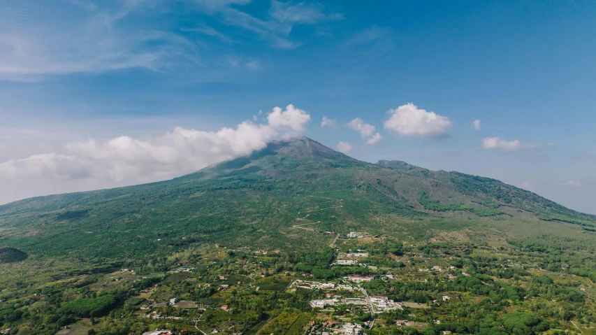 a mountain with a town below it, surrounded by trees