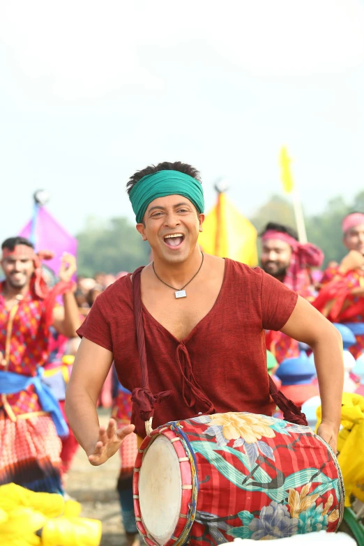 a man smiling as he plays the drums in front of people