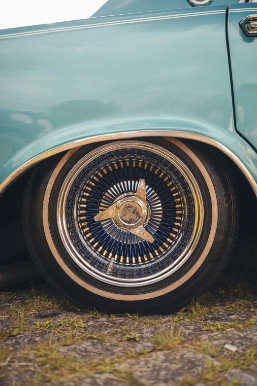 a colorful wheel on a light blue car with gold rims