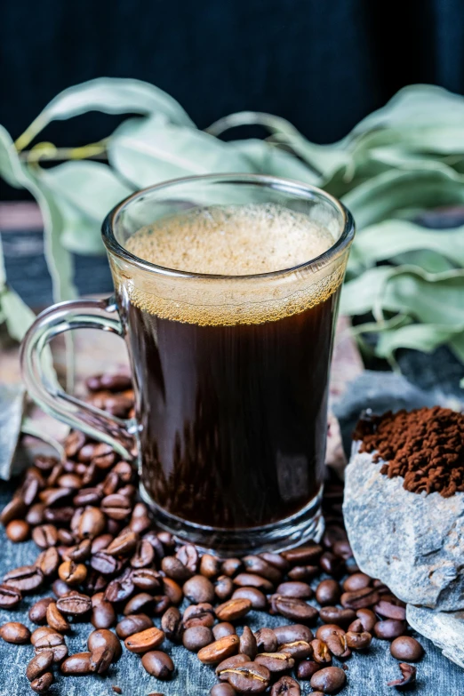 a glass cup full of coffee surrounded by coffee beans