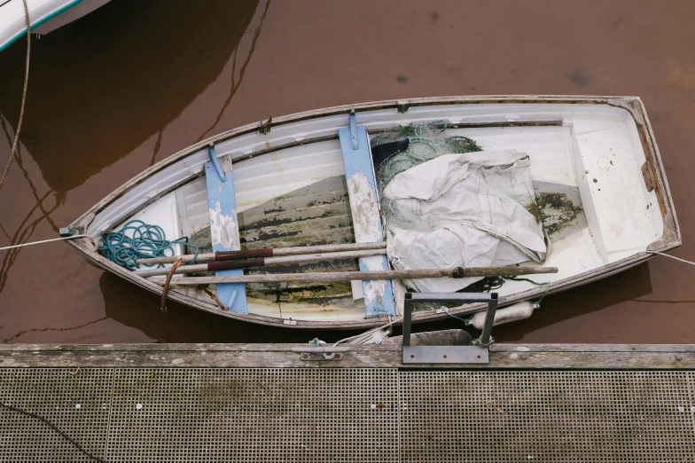 an old boat sitting in the water near a fence