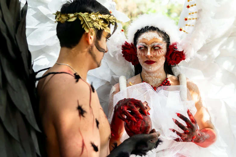 a man standing next to a woman that is covered in red paint