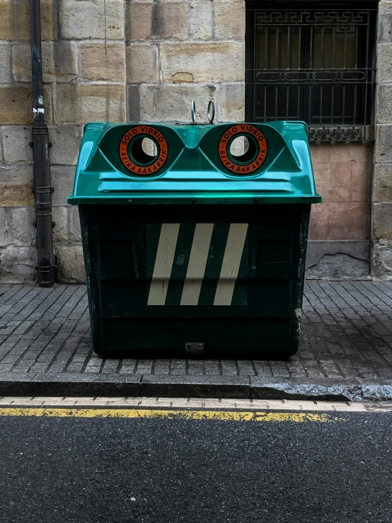 a large green box with two circular doors sitting on the sidewalk