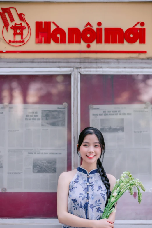 a girl with long hair holds flowers in front of a store