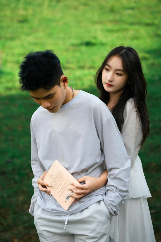 two asian s holding papers in a park