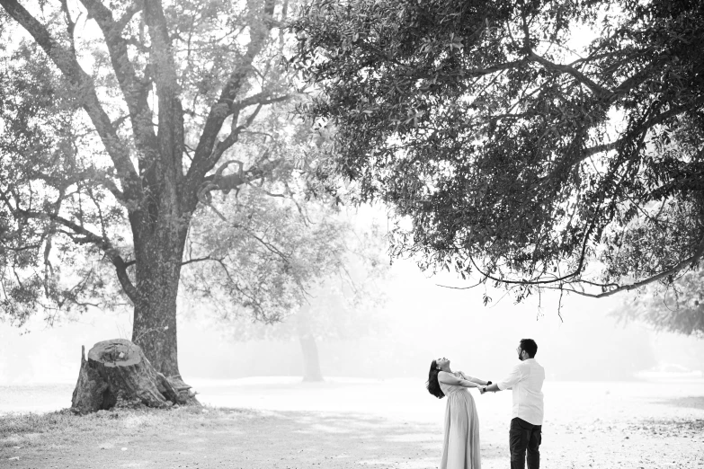 two people in a park under a big tree