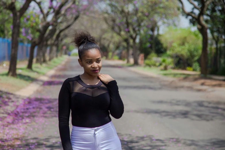 a girl in a black top is standing near a road