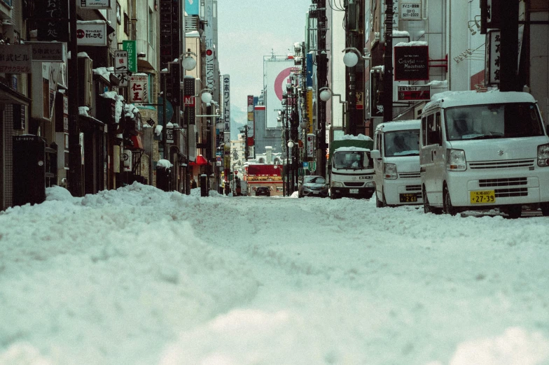 a truck parked in the street near many buildings covered in snow