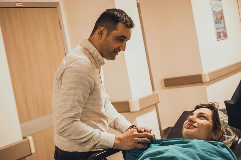 a person standing over a man who is lying on a bed