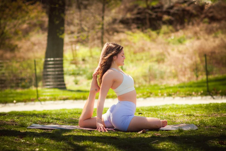 a woman is sitting on the grass doing yoga