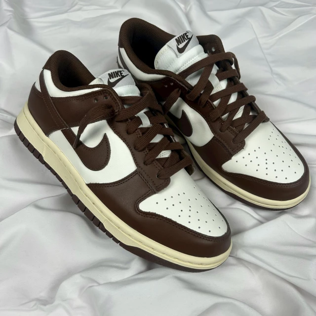 a pair of brown and white sneakers on a bed