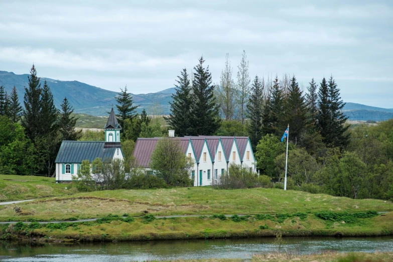 a grassy field and a house that is on the side of a river