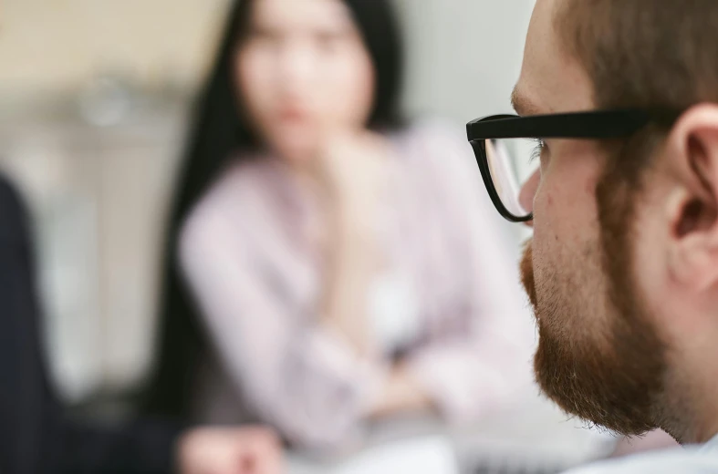 a woman sits in the background as two men stare on