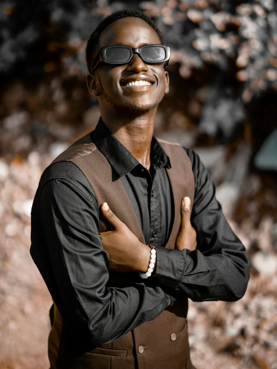 a man wearing glasses standing in front of a bush