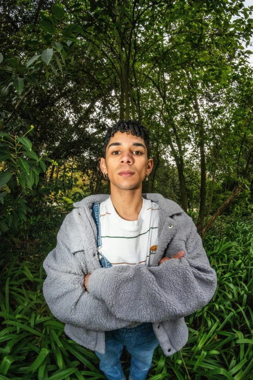 a man is standing by the grass with his arms crossed