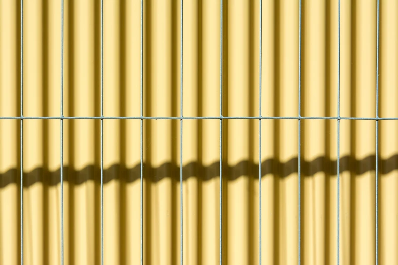 shadows on a yellow corrugated wall with no people on it