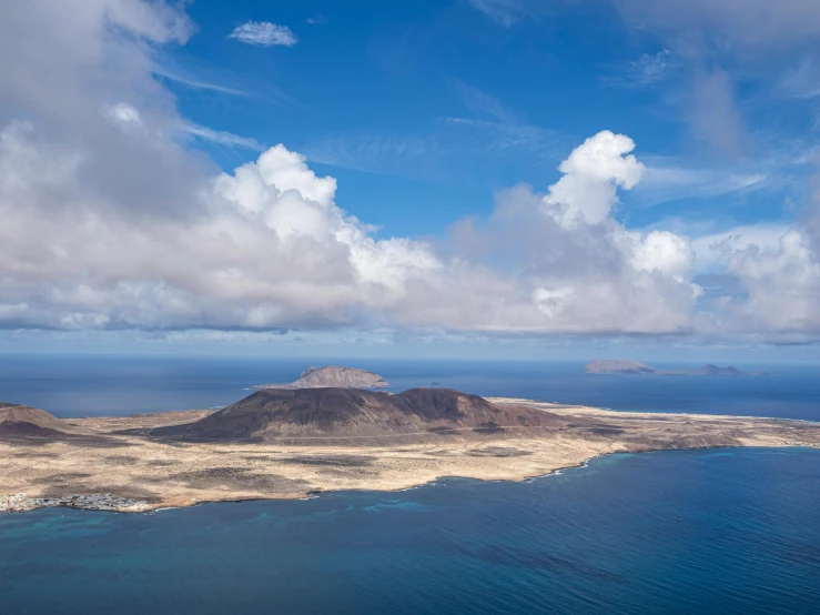 the ocean and land in front of some mountains