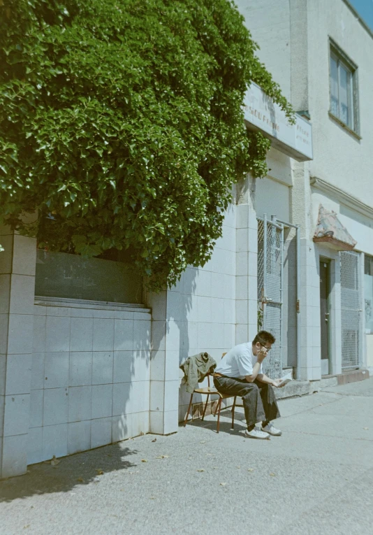 a man sits alone on a bench in front of a building