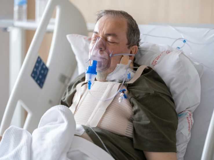 a man with an oxygen tube laying in a hospital bed