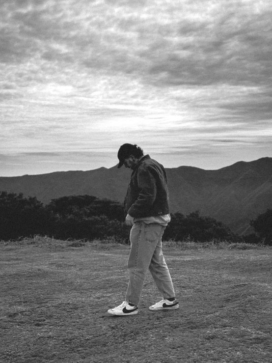 a person walking through an empty field near mountains