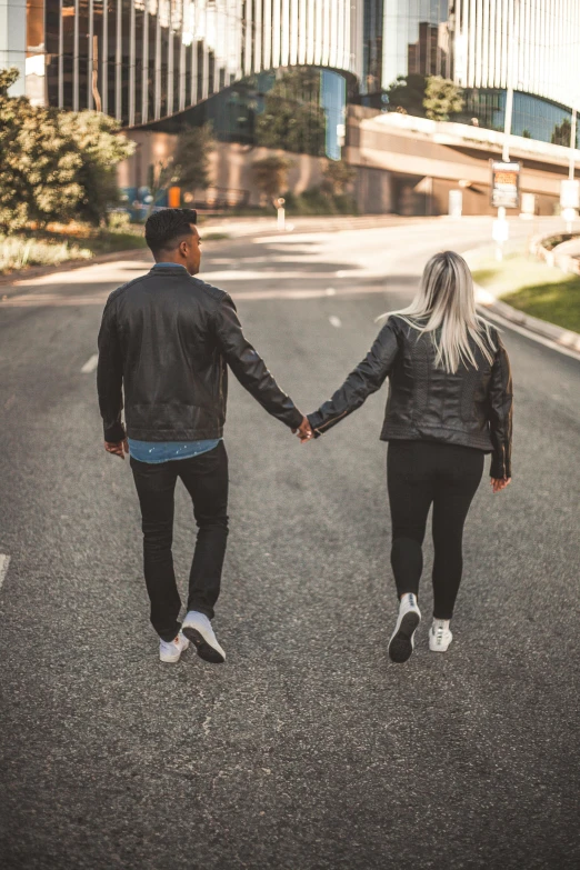 a young couple holding hands as they walk down the street