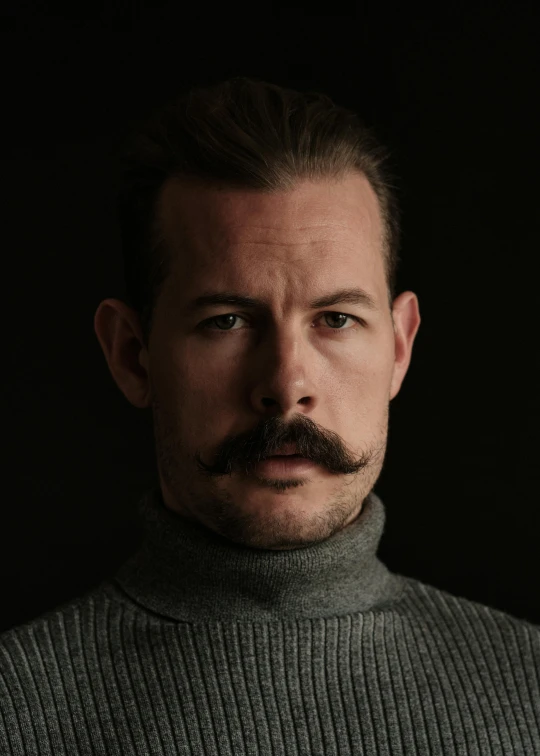 a man with a mustache and a turtle neck sweater