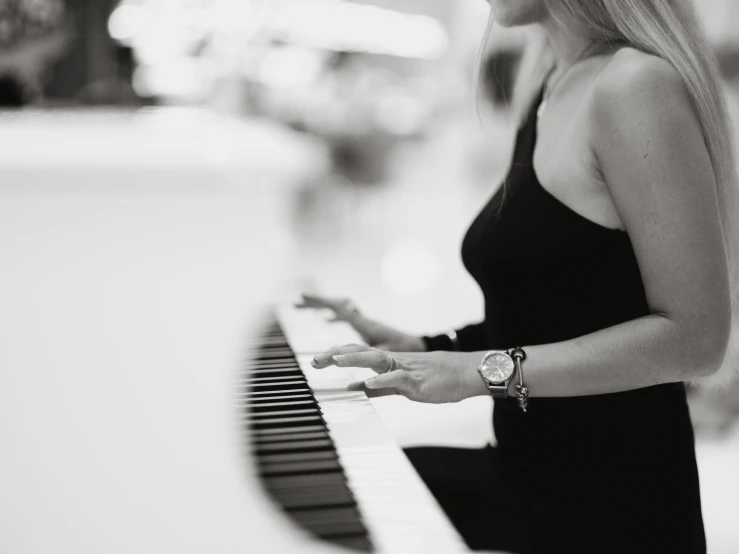 a girl sitting at a piano playing it with her hands