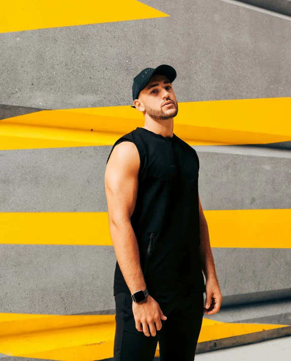 a man is wearing a black cap while standing near yellow lines