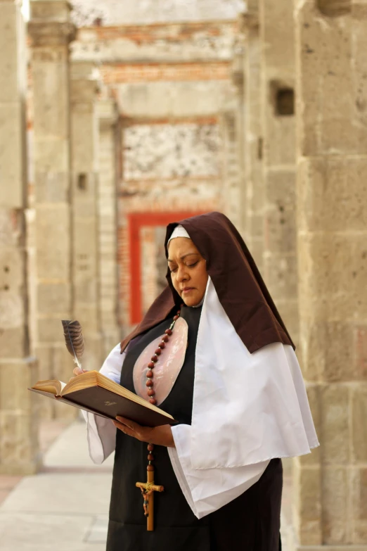 a woman dressed in a black robe holding an open book