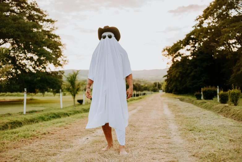 a man in sunglasses and a hat walking down a road