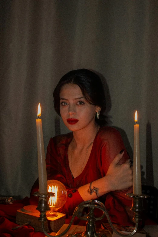 a woman sitting with candles behind her on a table