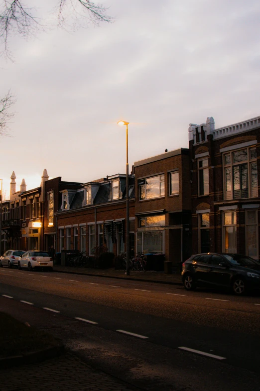 a dark street with parked cars on it next to some houses