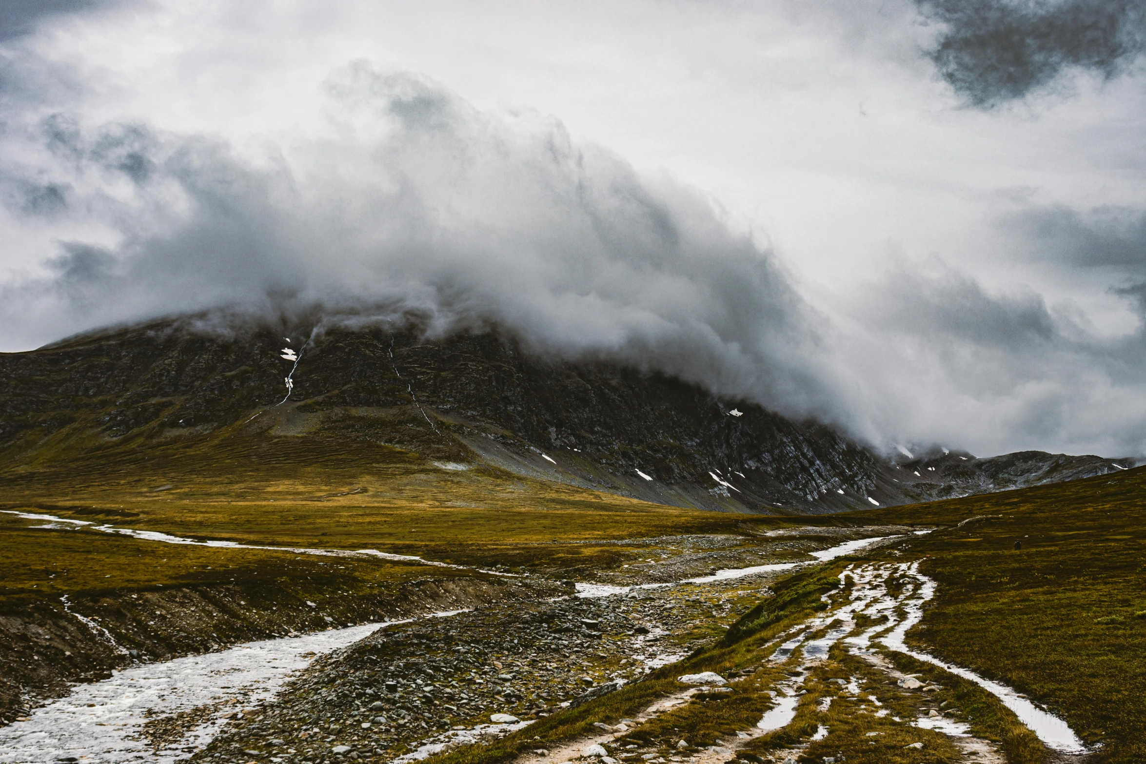 a narrow dirt road between mountains in the mountains