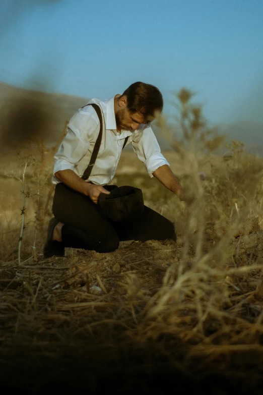 man in white shirt crouching with brown dog