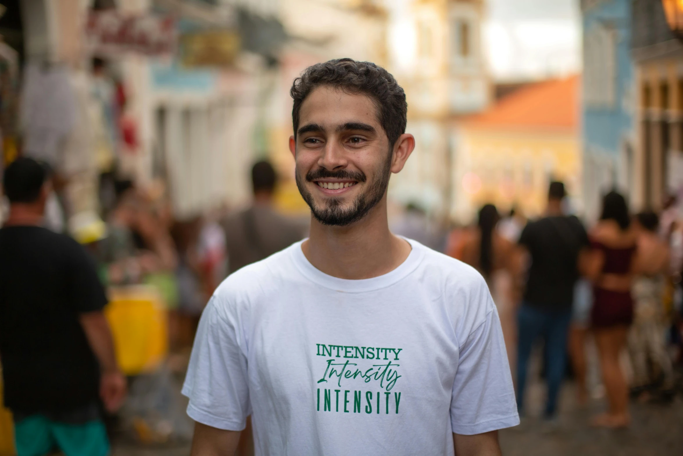 a young man smiles while standing in front of a crowd of people