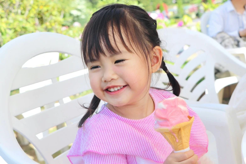 little girl holding a pink ice cream cone in her hand