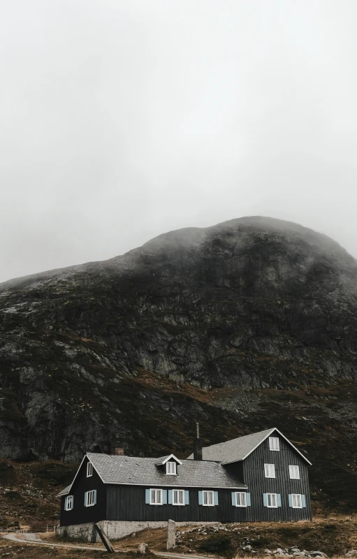 a large house near a grassy hill on a cloudy day