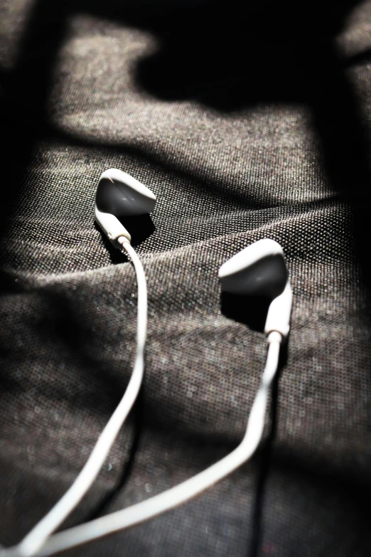 close up of ear buds plugged in on a bed