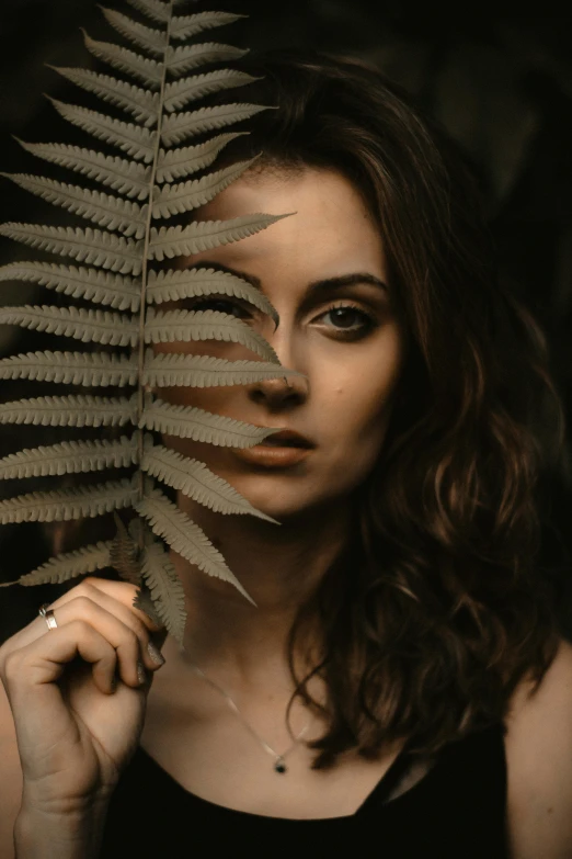 a woman with long hair holding a plant in her hands